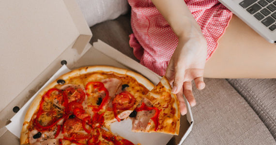 vrouw-ban-eet-pizza-computer