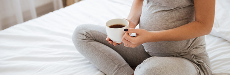 femme-enceinte assise-lit-cafe